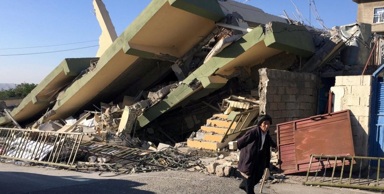 A man walks past a damaged building following an earthquake in Darbandikhan