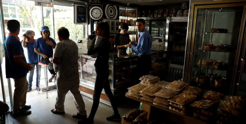 Customers walk out a bakery, during a massive blackout in Caracas Customers walk out a bakery, during a massive blackout in Caracas