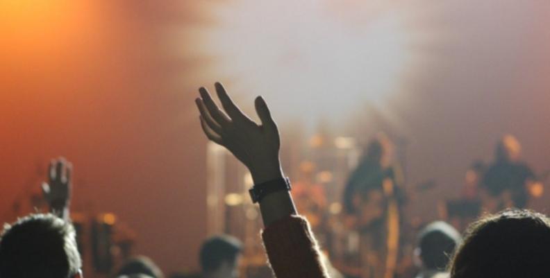 Agenda cultural en Bogotá Mujer alzando la mano en un concierto
