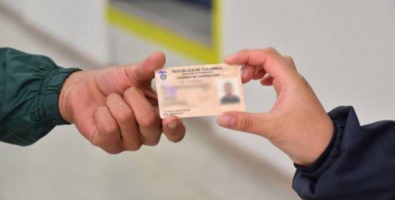 Licencias en Bogotá Una mano recibiendo una carnet de otra