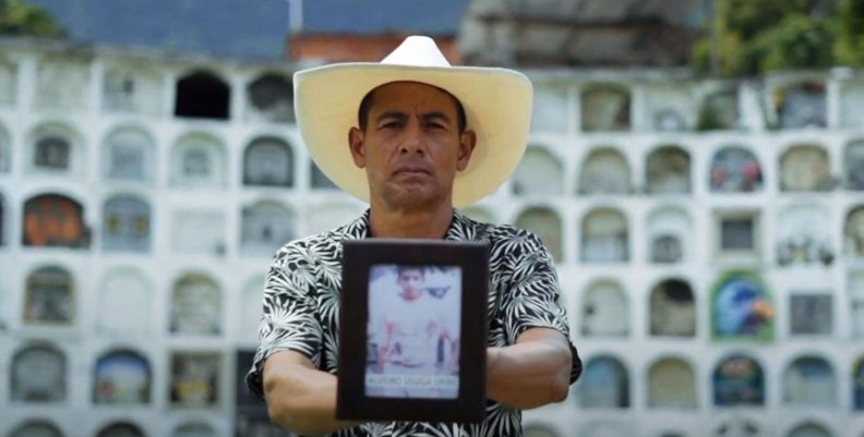 JEP Hombre sosteniendo una foto de una persona frente a cámara
