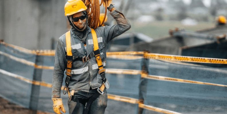 Un hombre con uniforme gris cargando cables