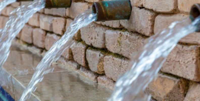 Agua cayendo por tubos de grifería