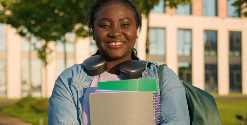 Jóvenes a la E Mujer sonriente con cuadernos en sus manos