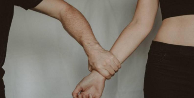 Un hombre apretando con fuerza el brazo de una mujer