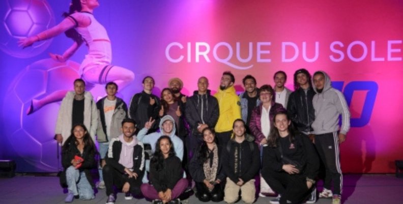 Cirque du Soleil Personas posando al frente de un cartel rosado