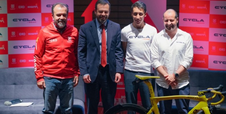 Egan Bernal Cuatro personas posando en una tarima atrás de una bicicleta amarilla