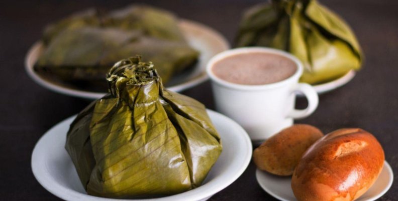 Tamal Plato de tamal con un pocillo de chocolate y pan al lado