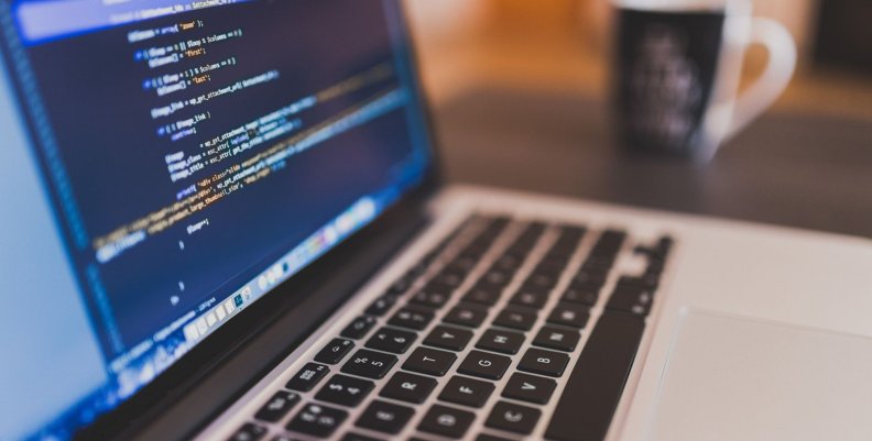 Talento TECH Computador con códigos de programación en la pantalla