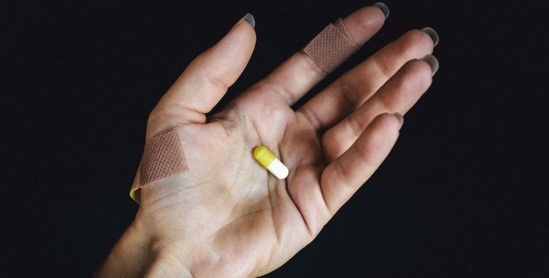 Desabastecimiento de medicamentos Mano sosteniendo una píldora amarilla