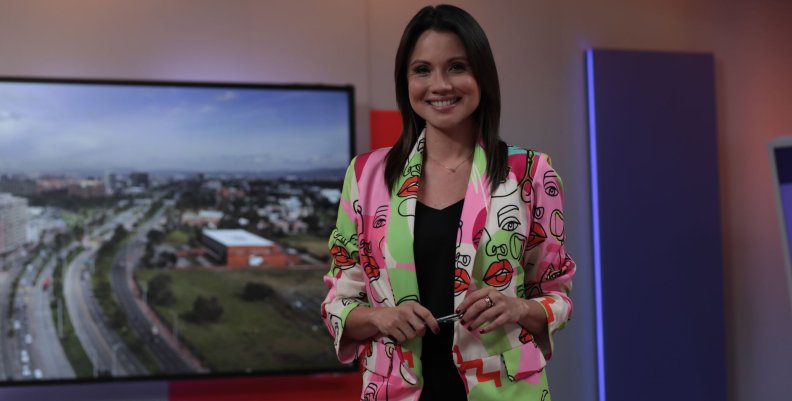 Mujeres de Canal Capital Mujer sonriente con blazer color rosa sobre un fondo morado