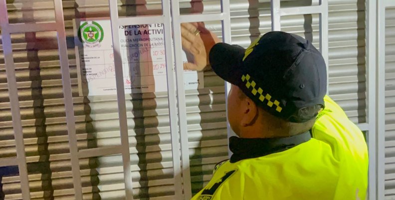 Licor adulterado Policía pegando un aviso de cierre en la reja de un establecimiento