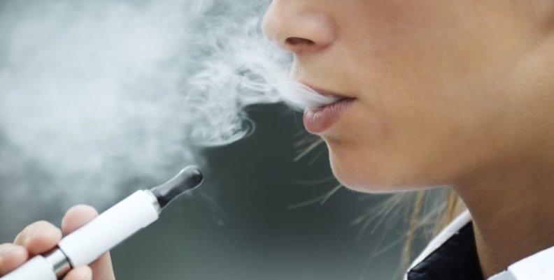 Cigarrillos electrónicos Mujer vapeando con un cigarrillo electrónico