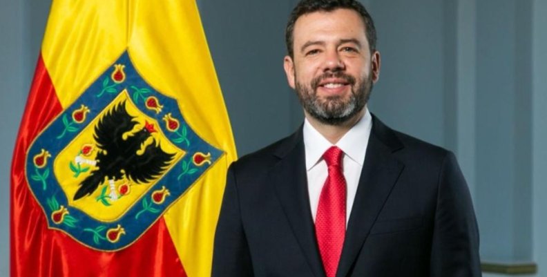 Carlos Fernando Galán Foto del alcalde Carlos Fernando Galán con traje negro, delate de una bandera de Bogotá