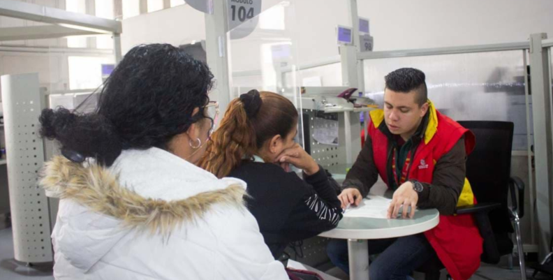 Dos mujeres sentadas al frente de un hombre con chaqueta roja
