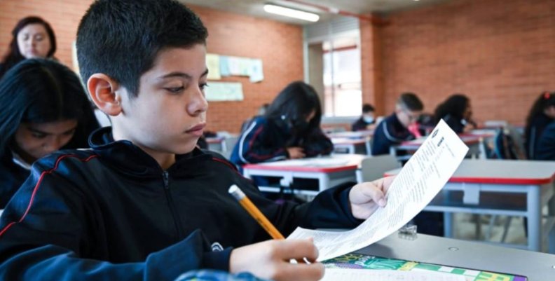 Colegio Santa Bárbara Niño con una hoja y un lápiz en la mano