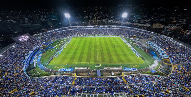 Millonarios FC Vista panorámica de un estadio de fútbol. Los hinchas visten prendas azules y el cielo está de noche