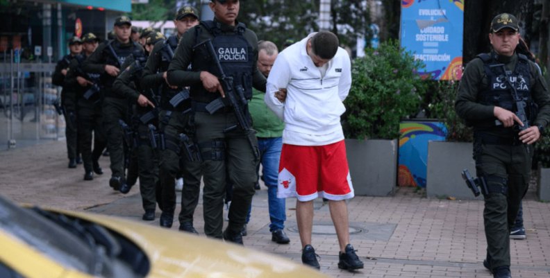 Los de la T Policías armados custodiando a un hombre con hoodie blanco y shorts rojos