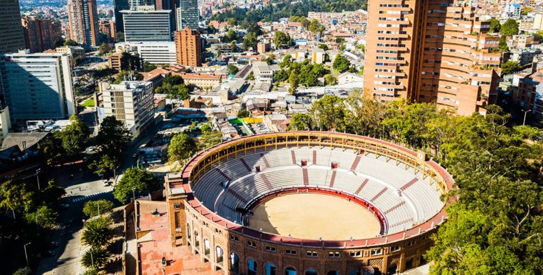 Una plaza de toros con dos torres de edificios detrás