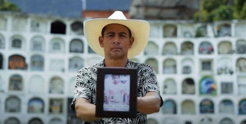 Un hombre sosteniendo un retrato de su hijo en sus manos
