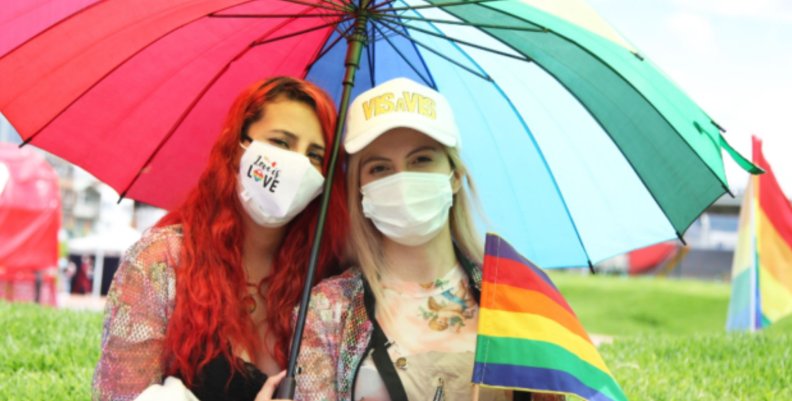Dos mujeres bajo una sombrilla de colores