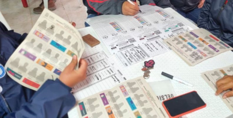 Elecciones locales. Manos encima de una mesa en la que aparecen papeles de votación para una elección local.