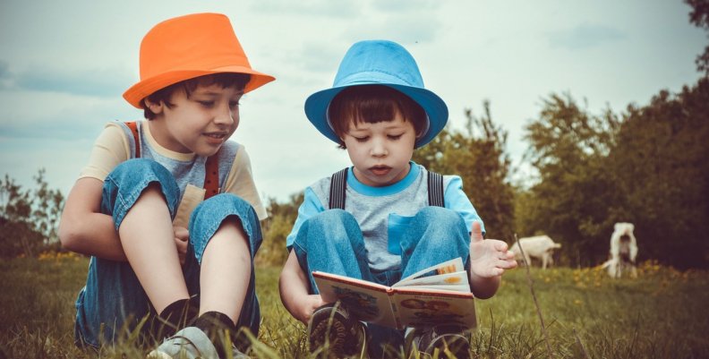 FILBO Dos niños en el césped leyendo un libro