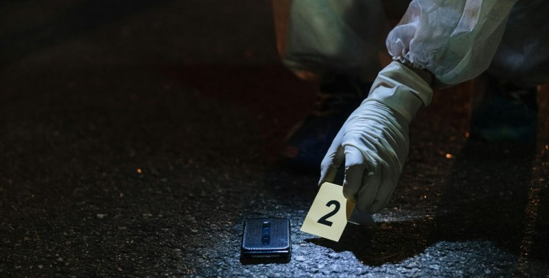 Crimen Forense en medio de una escena del crimen con el número 2 en la mano