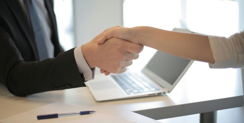 Empleo Dos personas estrechándose las manos durante una entrevista de trabajo