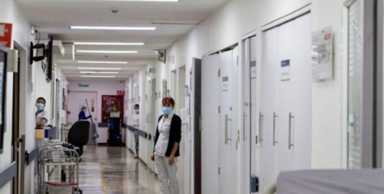 Hospitales Bogotá Imagen del pasillo de un hospital en Bogotá con pacientes asomándose desde las puertas de las habitaciones.