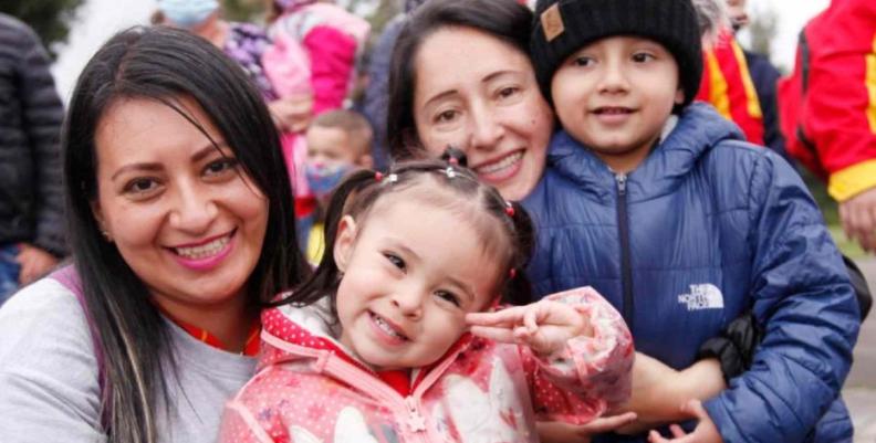 Dos mujeres adultas junto a dos niños abrazados y sonriendo 