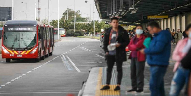 Varias personas es una de las estaciones de TransMilenio esperando su ruta 