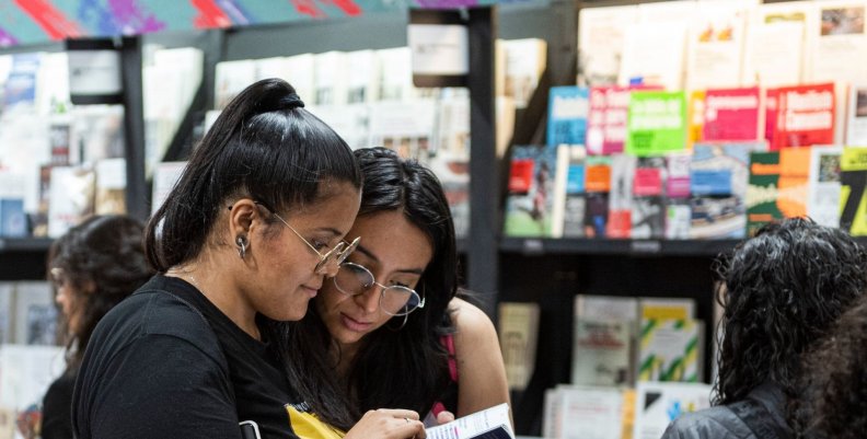 Dos mujeres leyendo libros en la FILBo 