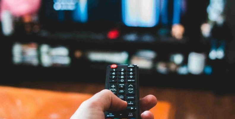 Una persona con un control remoto en la mano a punto de cambiar algo en su televisor