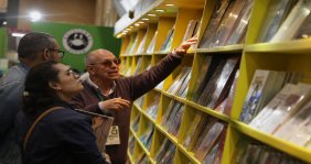 Personas mirando libros en una estantería en la Filbo
