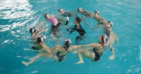 Varias personas haciendo una formación en círculo en una piscina