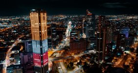 Vista panorámica de Bogotá de noche: se ve un rascacielos con la bandera de Colombia