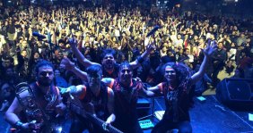 Una banda posando detrás de un público lleno de personas