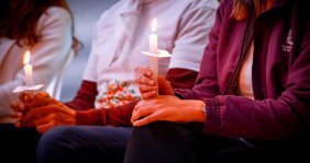 Tres personas, cada una sosteniendo una vela encendida en sus manos 