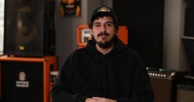 Un hombre con hoodie negro y gorra en un estudio de grabación