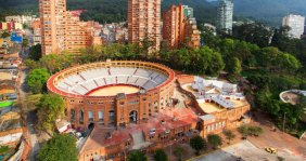 Plaza de toros color ladrillo. Atrás hay unas torres de apartamentos