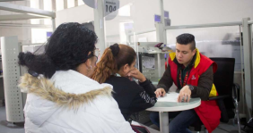 Dos mujeres sentadas al frente de un hombre con chaqueta roja
