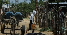 Un hombre cargando unos bidones de agua