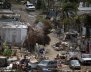 A man carrying a water container walks next to damaged houses after the area was hit by Hurricane Maria in Canovanas