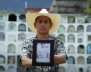Hombre sosteniendo una foto de una persona frente a cámara