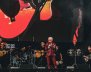 Hombre con traje morado con brillantes, en medio de una tarima con músicos