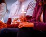 Tres personas, cada una sosteniendo una vela encendida en sus manos 