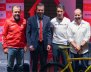 Cuatro personas posando en una tarima atrás de una bicicleta amarilla