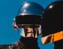 Miembros del dúo Daft Punk con sus cascos en un fondo azul