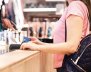Mujer de blusa rosada haciendo una compra con una tarjeta azul